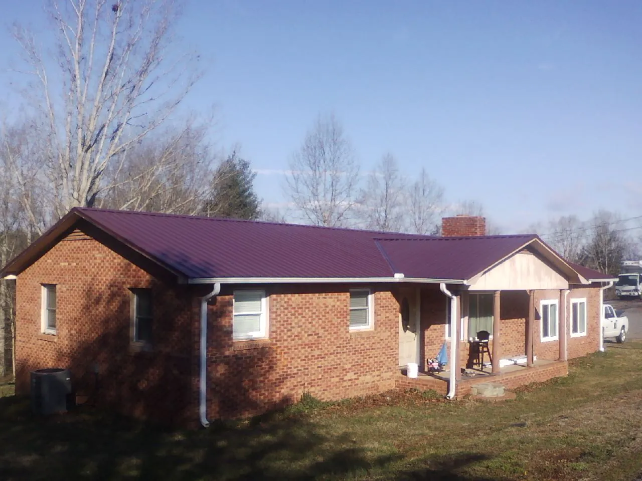 Burgundy metal roof on a brick ranch home with a new addition in South Dennis